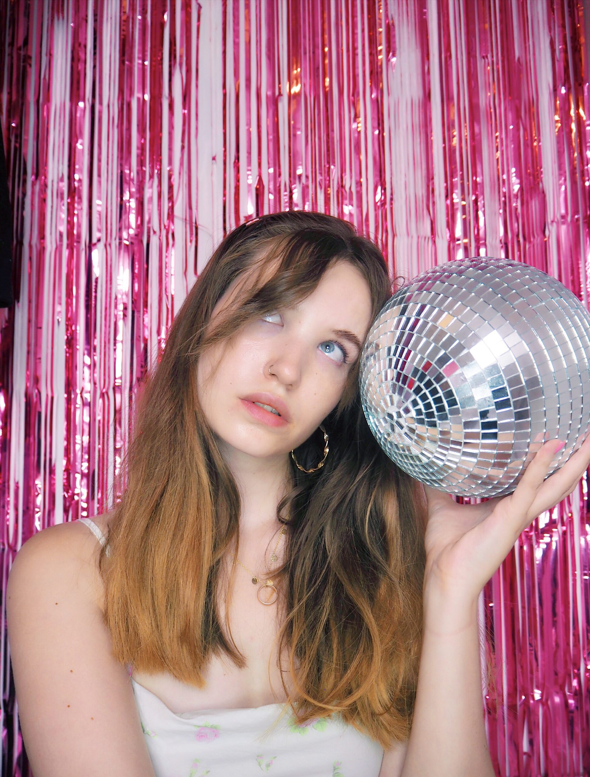 Wedding copywriter leaning on a silver disco ball at a pink party