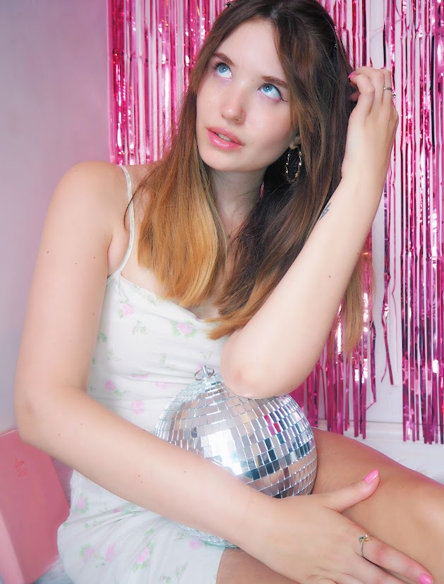 Website copywriter and business owner wearing white floral dress with pink part streamers and a disco ball