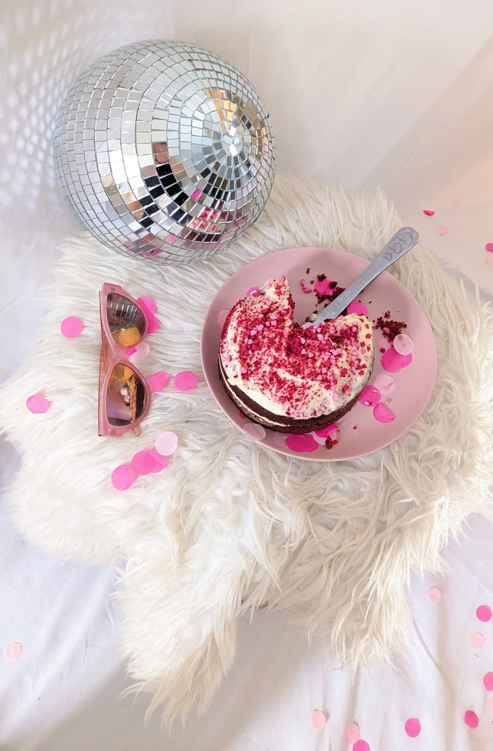 Pink party scene with cake, disco ball, sunglasses, and confetti