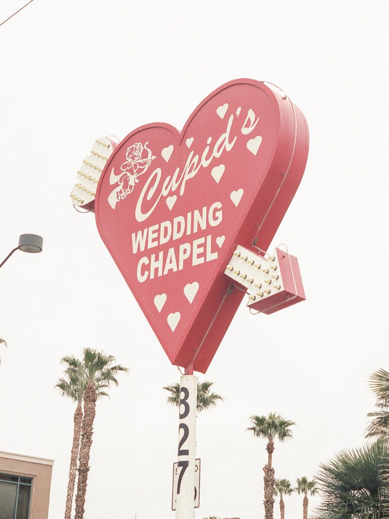 Cupid's chapel in Las Vegas. A pink heart sign with an arrow through says 'Cupid's wedding chapel' and has a picture of cupid and his bow.